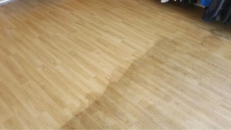 A vinyl safety floor in a charity shop during a deep clean. The left side shows the cleaned area and the right side is still visibly dirty. A very noticeable difference.