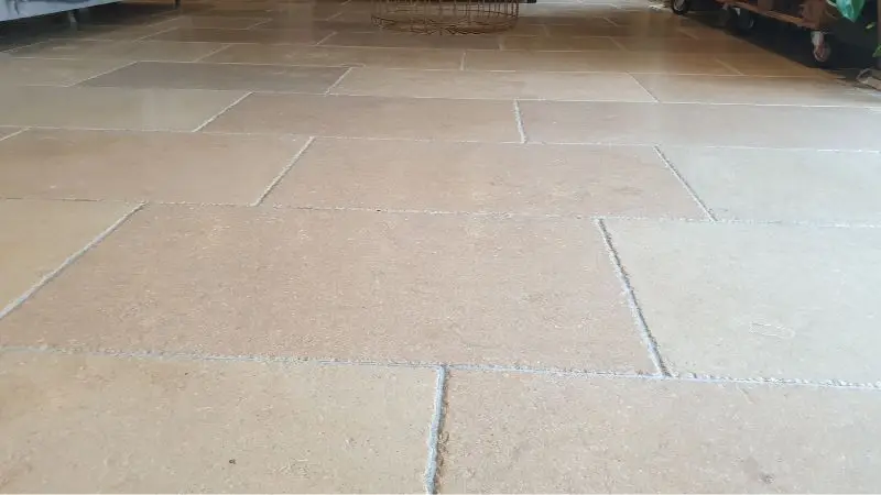 A low down image of a clean limestone floor. The tiles are beige with white grout.