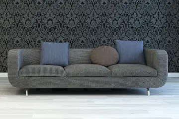 A grey fabric 3 seater sofa with 2 blue square scatter cushions and 1 brown circular scatter cushion.