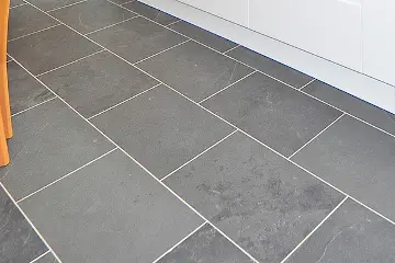 A grey tiled floor with bright white grout lines.